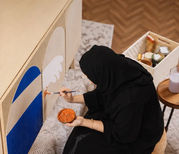 An Emirati woman hand-painting a cabinet for the Homes R Us activation